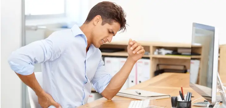 a man sitting in a desk suffering from back pain